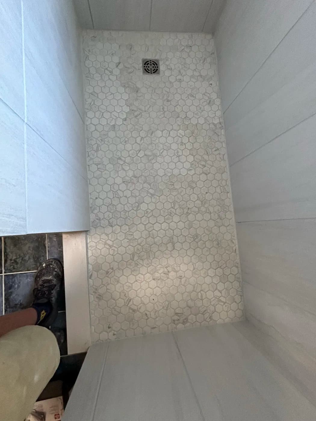 Walk-in shower with marble hexagon tile floor and large format wall tile